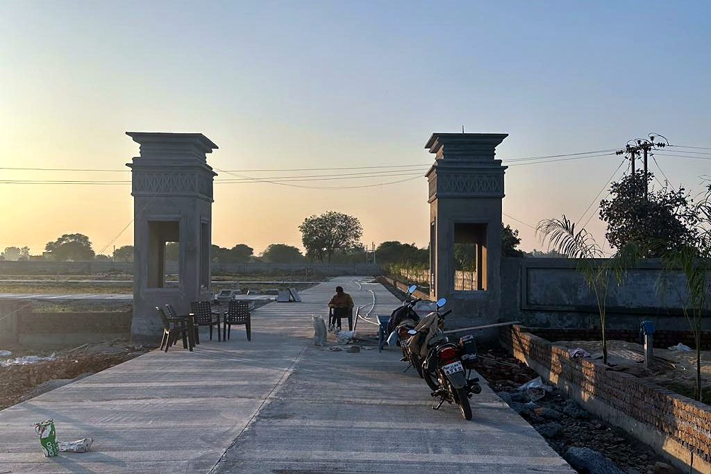 Two concrete gate pillars either side of a new concrete road at sunset at the entrance of Parvati Ratna Residency township, Mandsaur